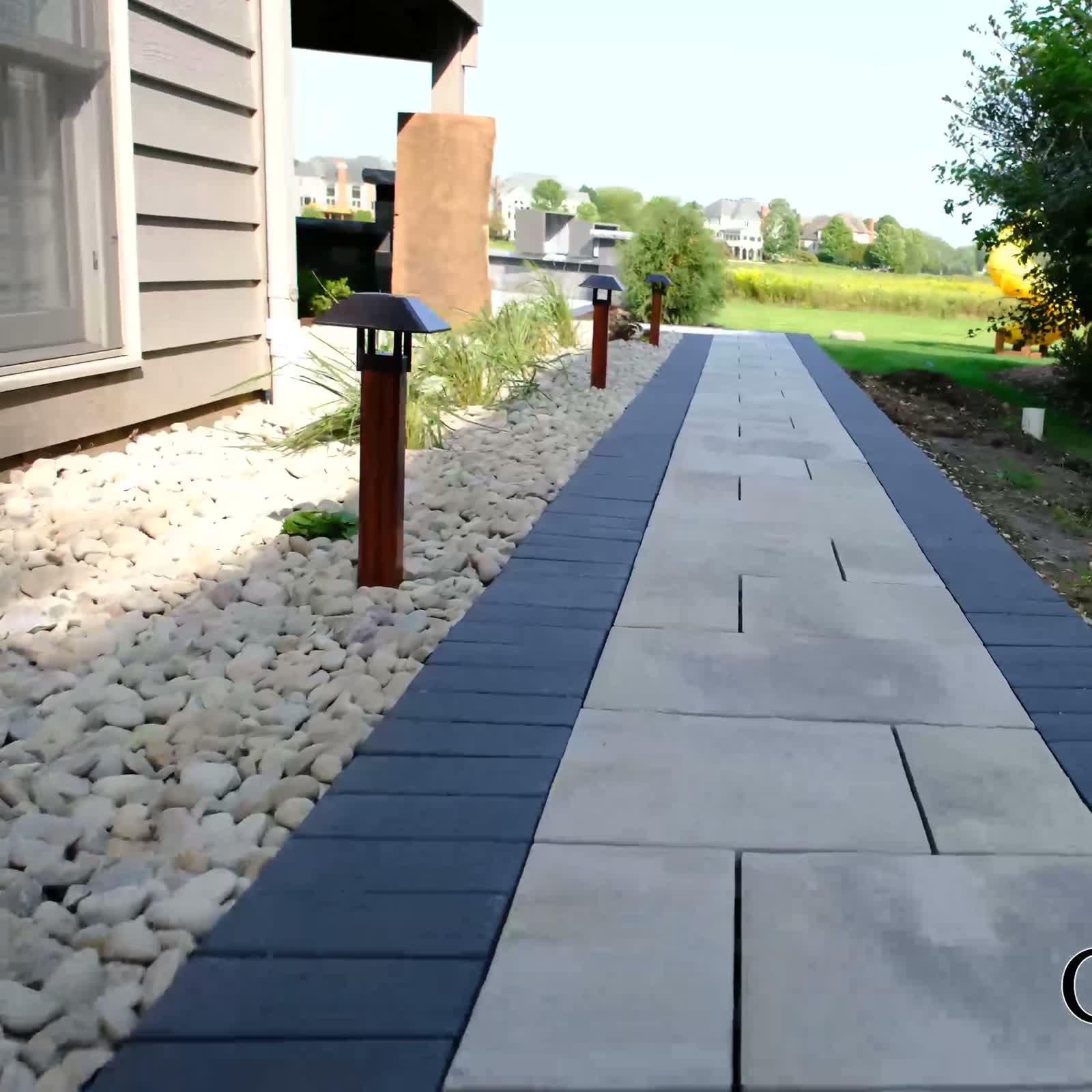 Bluestone walkway with charcoal paver border and river-rock bed
